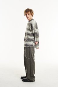 Megztinis su žaliais ir pilkais juostelėmis, tekstūruotas mezginys. Laisvai krentantys pilki kelnių su šoniniu kišeniu ir sidabro grandinėlės detale. Juodi platforminiai batai.