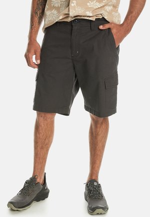 Black cargo shorts made of durable fabric with a relaxed fit, featuring side pockets and a flat front. Worn with gray athletic shoes.
