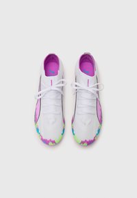 White athletic shoes with purple accents, textured fabric, and a colorful gradient design on the sole. Laces are white, with pink detailing.
