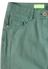 Pantalones de mezclilla verdes con una textura suave, que cuentan con un bolsillo frontal con un botón decorativo y costuras en contraste en la cinturilla.