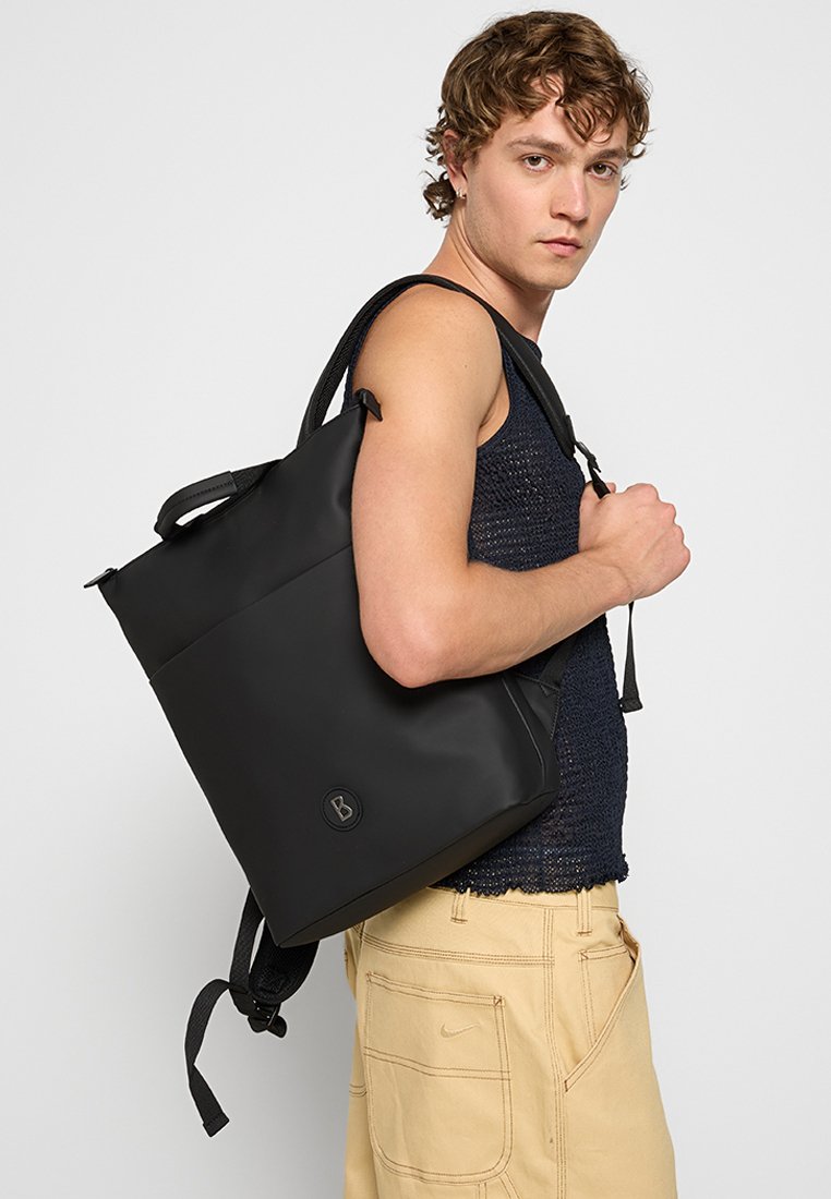 Sac à dos noir avec une texture lisse et imperméable. Dispose de deux poignées, de bretelles ajustables et d'un logo circulaire. Design simple et structuré.