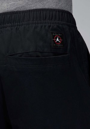 Črne atletske kratke hlače z elastiko v pasu, z zadnjim žepom in znakom Jordan Brand v rdeči in beli barvi.