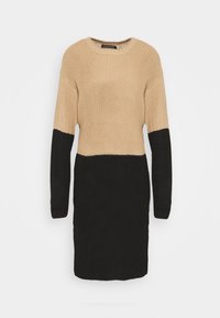 Stickad klänning med en beige överdel och en svart underdel, med långa ärmar och rund halsringning. Strukturerad tyg.