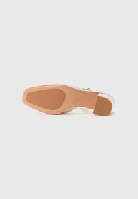 Scarpa con tacco alto trasparente e tomaia in plastica trasparente, con suola color nude. Il design presenta una punta quadrata e un tacco sottile.