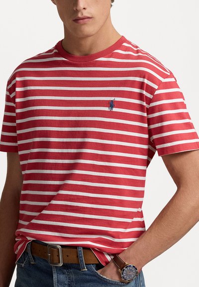 Randig t-shirt i röd och vit med rund hals och korta ärmar; har en liten broderad blå logotyp på bröstet. Avslappnad passform.