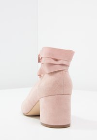 Růžová suede kotníková bota s texturovaným povrchem, se zřaseným žebrovaným materiálem na okraji a blokovým podpatkem.