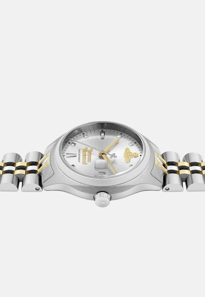 Zilveren horloge met een ronde wijzerplaat, gouden accenten en een band van roestvrij staal. Heeft een gestructureerde zilveren wijzerplaat en een prominente kroon aan de zijkant.