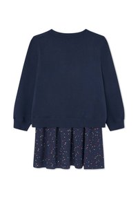 Sudadera azul marino de manga larga, combinada con una falda plisada que presenta un patrón de manchas multicolores sobre un fondo oscuro.