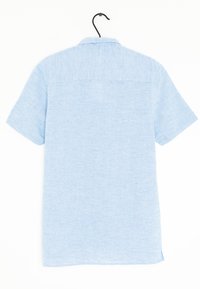 Camicetta a maniche corte e bottoni in tessuto blu chiaro, caratterizzata da una trama testurizzata, orlo dritto e un dettaglio in yoke sul retro. Appesa a un gancio nero.