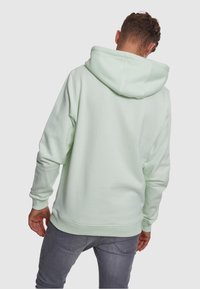 Mintgrüner Kapuzenpullover aus weichem Stoff, mit gerippten Bündchen und Saum, in entspannter Passform ohne sichtbare Logos oder Muster.