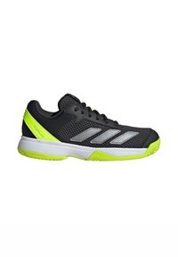 Chaussure de sport noire avec tige en maille, rayures argentées et accents vert vif. Elle présente une semelle intermédiaire blanche et une semelle en caoutchouc texturée pour une meilleure adhérence.