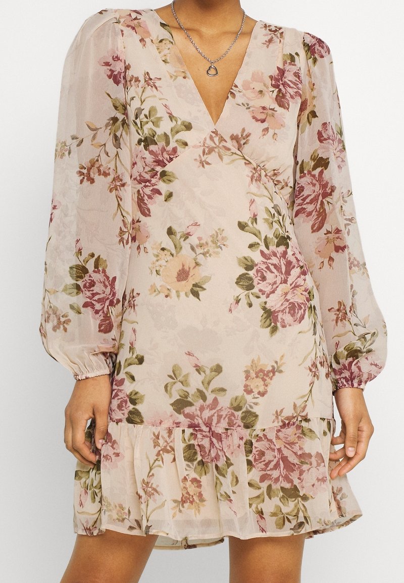 Vestido floral de tejido semitransparente, con escote en V, mangas largas abullonadas y un dobladillo con volantes. Los colores incluyen rosa suave, verde y burdeos.