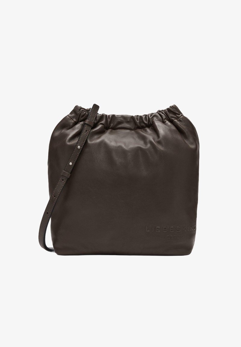 Brązowa skórzana torba ze sznurkiem do zaciągania, o miękkiej fakturze, zaokrąglonym kształcie i regulowanym pasku. Z przodu znajduje się wytłoczone logo.