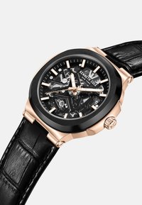 Kwarts horloge met een zwarte skeletwijzerplaat, roségouden accenten en een zwarte leren band met een gestructureerde afwerking.