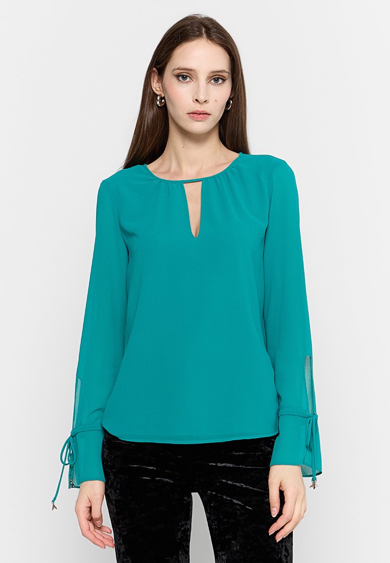 Tee-farbene Bluse aus leichtem Stoff mit einem Schlüssellochausschnitt, langen Ärmeln und Bindebändern an den Manschetten. Schlichtes Design mit glatter Textur.