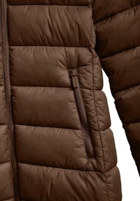 Brun puffjacka med horisontell quiltning, som har en sidoficka med dragkedja, slät textur och matchande brun dragkedjedetalj.