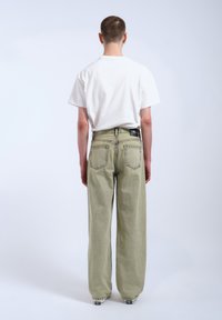 Lösa, ljus olivgröna denimbyxor med hög midja, fyra fickor och en svart etikett bakifrån.