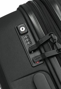 Valise rigide noire équipée d'une serrure approuvée par la TSA, de cadrans à combinaison et de doubles fermetures éclair avec une finition texturée pour plus de durabilité.