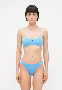 Modrý bikinový set vyrobený z hladkej látky; bandeau top s tenkými ramienkami a malým čiernym logom; nohavičky s nízkym pásom a bezšvovými okrajmi.