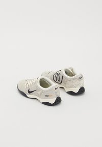 Zapatillas deportivas Nike con un upper texturizado en gris claro, cordones crema, acentos negros y el logotipo 'total90' en el lateral.