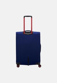 Valigia blu navy con una texture liscia, manico rosso telescopico e quattro ruote rosse girevoli per una mobilità facile. Forma rettangolare di base.