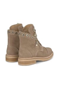 Botines de ante marrón con ojales metálicos, herrajes decorativos y un tacón de madera. Presentan un diseño clásico de cordones y detalles de costura.