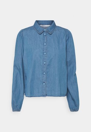 Camisa de mezclilla azul claro con cuello puntiagudo, mangas largas abullonadas, cierre de botones en la parte delantera y un dobladillo corto. Textura suave y diseño casual.