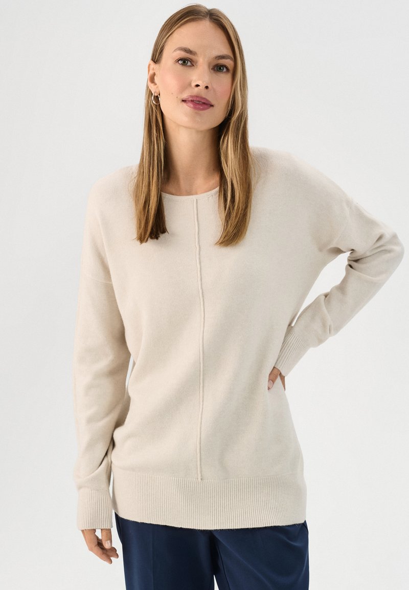 Beige gebreide trui met een ronde hals, lange mouwen, geribbelde manchetten en een geribbelde zoom. Kenmerkt zich door een naad in het midden voor een extra ontwerpdetail.