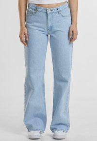 Lyseblå denim bukser med vide ben og høy midje, frontlommer og knapplukking. Har en jevn tekstur og minimal søm.