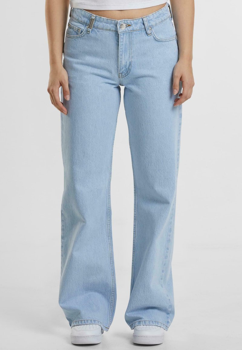 Lyseblå denim bukser med vide ben og høy midje, frontlommer og knapplukking. Har en jevn tekstur og minimal søm.