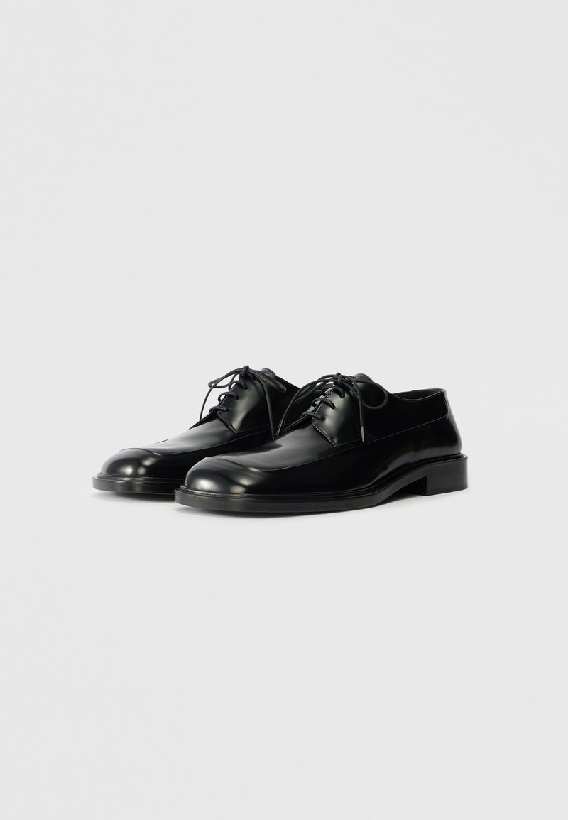 Scarpe oxford in pelle nera con texture liscia, punta arrotondata, design con lacci e tacco basso e impilato.