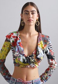Bloemmotief, langmouw crop top met een diepe V-hals en een gerimpelde zoom; meerkleurige stof met diverse bloemen- en geometrische ontwerpen.