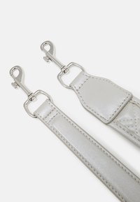 Sangle argentée métallique avec un design plat, une texture brillante, et des fermoirs en métal argenté aux deux extrémités pour un attache sécurisée.