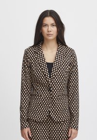 Karierter Blazer in Braun und Schwarz, mit tailliertem Schnitt, Reverskragen, einreihiger Knopfverschluss und zwei vorderen Taschen.