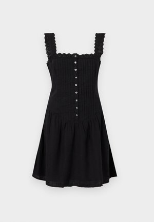 Černé šaty bez rukávů s krajkovými ramínky s oblými okraji, knoflíky vpředu, vertikálními sklady na živůtku a rozšířenou sukní pod pasem.