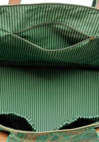 Tasje met rits aan de binnenkant, voorzien van een groen, gestreept stof met een contrasterende, patternd bodem en een extra ritsvak.