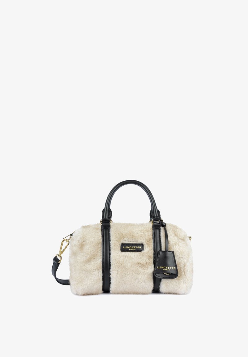 Petit sac à main beige en fausse fourrure avec poignées en cuir noir, bordure, une bandoulière et logo Lancaster Paris sur le devant et l’étiquette.