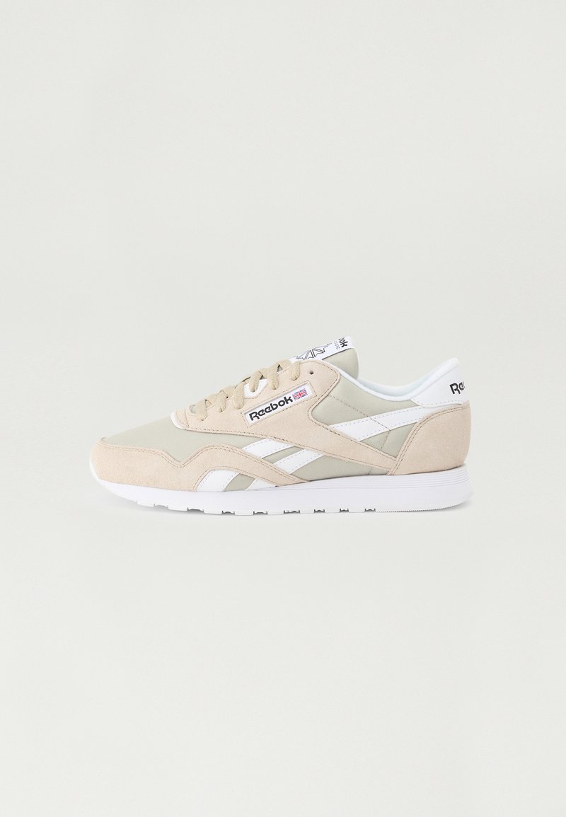 Beige sneakers med en kombinasjon av semsket skinn og mesh overdel. Hvide detaljer på sidene, tungen og sålen. Forsterket tå og polstret krage.