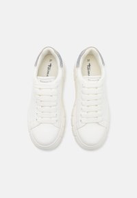 Paire de baskets blanches à lacets avec semelles épaisses et détail en strass argenté sur le talon, vue de dessus.