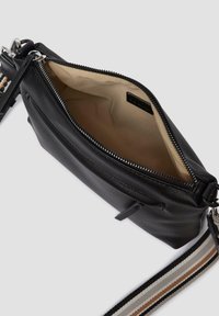Borsa a tracolla in pelle nera con apertura zip e interno beige. Caratterizzata da una tracolla in tessuto a righe e una piccola tasca esterna.