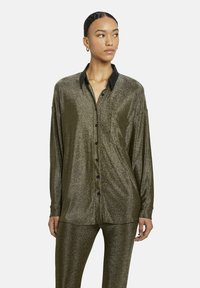Langsleeve, metallic olijfgroene shirt met een zwarte kraag, knoopsluiting aan de voorkant en borstzak, gemaakt van een zachte, textuurrijke stof.