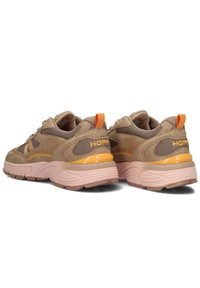 Sneakers marroni con materiale in rete e scamosciato, accenti arancioni a contrasto, forma arrotondata e suole spesse rosa. Logo visibile sul tallone.