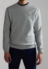 Sudadera gris claro hecha de una mezcla de algodón, con un cuello redondo y puños y bajo acanalados. Pequeño logo de bandera roja y azul en el pecho.