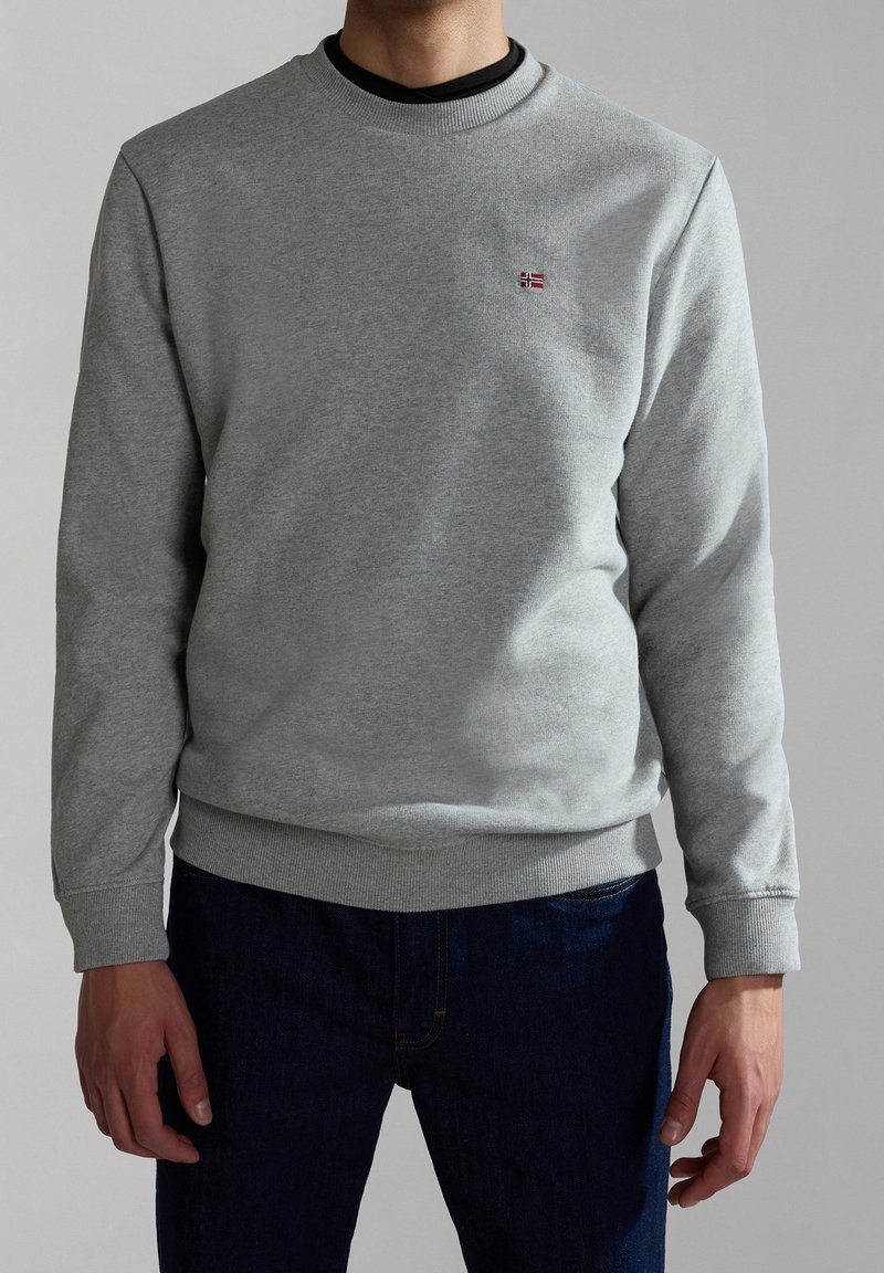 Sudadera gris claro hecha de una mezcla de algodón, con un cuello redondo y puños y bajo acanalados. Pequeño logo de bandera roja y azul en el pecho.