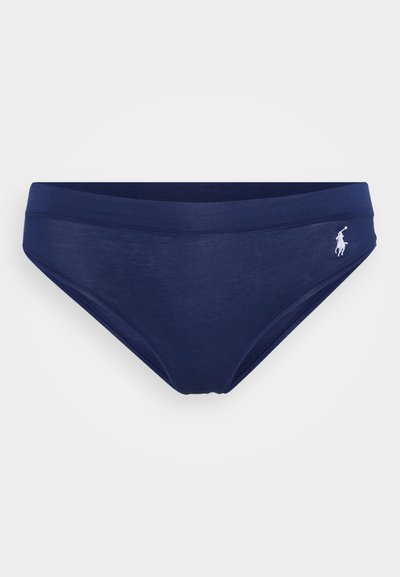 Tums navy zils peldkostīms, kas izgatavots no elastīga auduma, ar platām jostām un diskretu baltu polo logotipu kreisajā pusē. Gluda tekstūra.