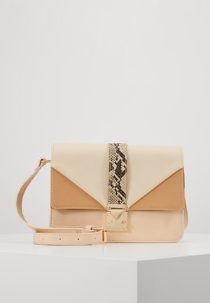 Beżowa i jasnobrązowa skórzana torba na ramię z paskiem w motyw skóry węża oraz złotym zapięciem, leżąca na białej powierzchni.