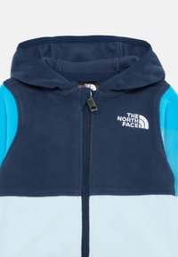 Sweatshirt de felpa com fecho éclair, apresentando painéis em azul marinho, azul claro e turquesa. O logótipo The North Face está impresso na parte superior esquerda do peito.