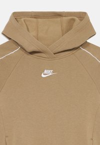 Sweat à capuche marron en tissu doux avec des accents de couture blanche et un petit logo Nike blanc sur la poitrine.