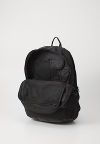 Črn nahrbtnik z gladko zunanjostjo, zadrgami, notranjimi mrežastimi žepi in teksturirano oblogo. Ima glavni predel in sprednji žep z zadrgo.