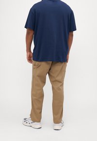 Tmavě modré bavlněné tričko s volnějším střihem, doplněné světle hnědými cargo kalhotami s postranními kapsami a rovnými nohavicemi.